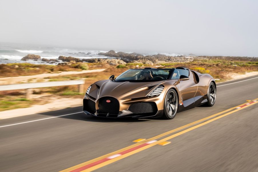 A bronze Bugatti Mistral roadster races along the seashore.