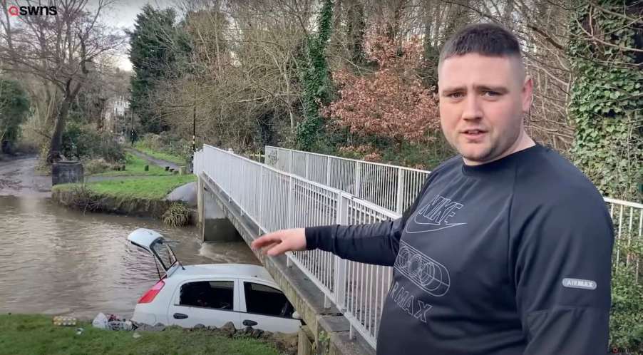 U.K. hero explaining how he used ratchet straps to save a mother and toddler from the sinking car visible in the background.