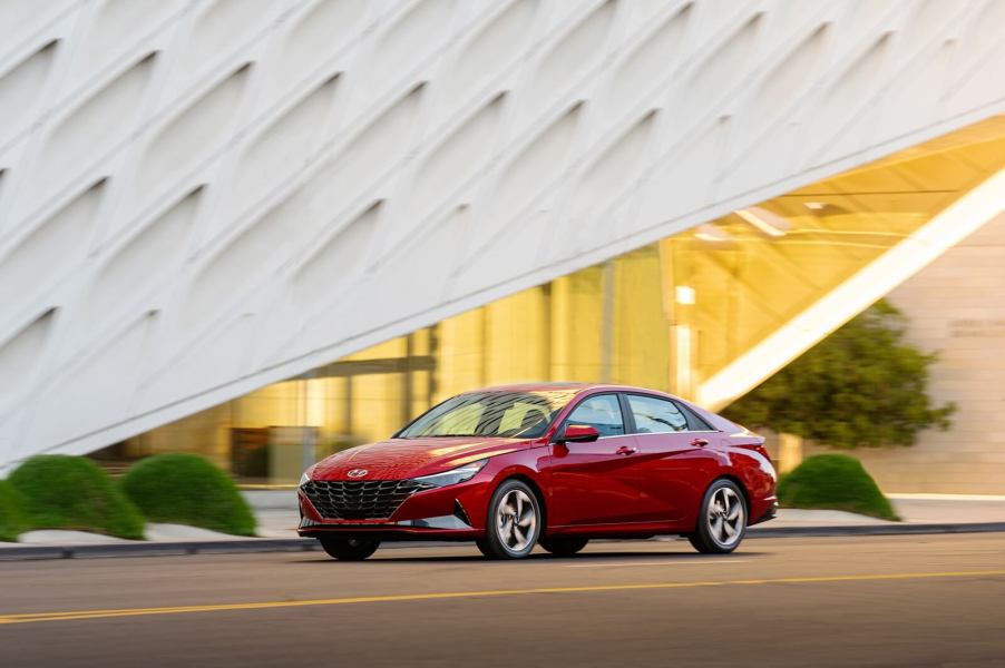 A 2021 Hyundai Elantra cruises by an modern structure.