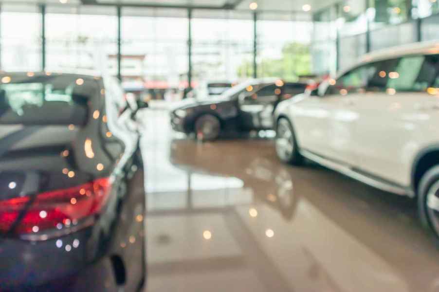 A blurry daylight shot of inside of dealership showroom several cars parked in view