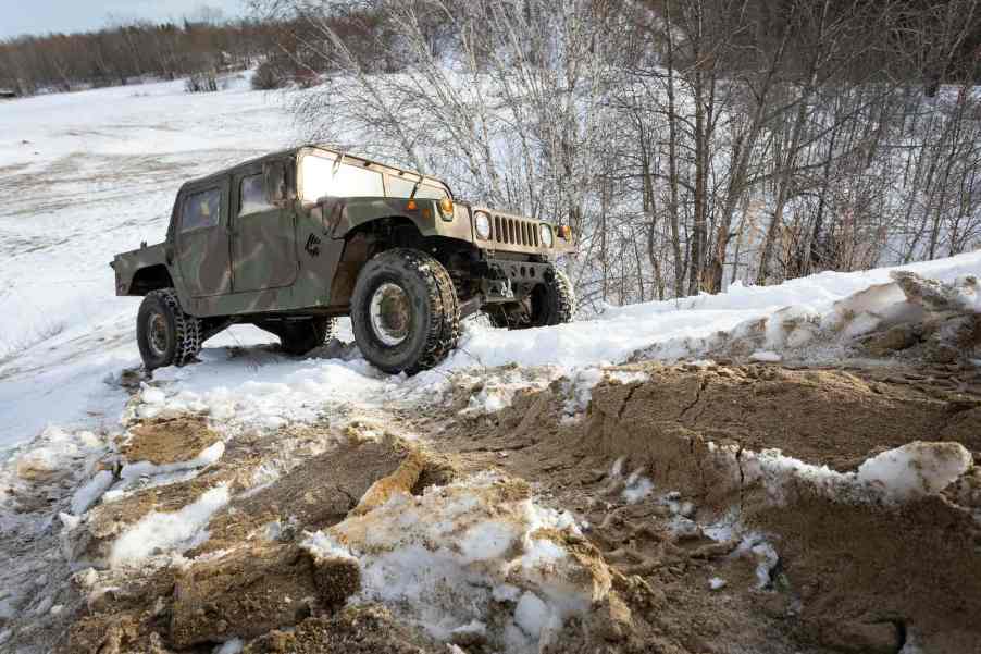 Military surplus Humvee SUV navigating an off-road trail.