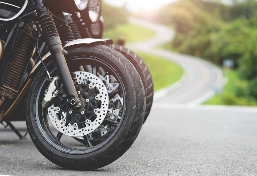 Motorcycles park right next to each other before sharing a two lane route out into the country.