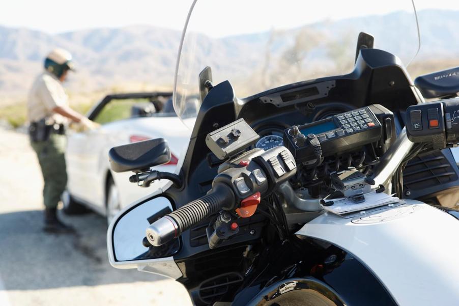 A California Highway Patrol Officer dispenses a ticket after getting off a motorcycle.