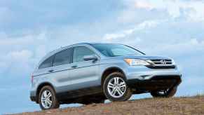 A blue 2010 Honda CR-V parked on a dirt hill in right front angle profile view