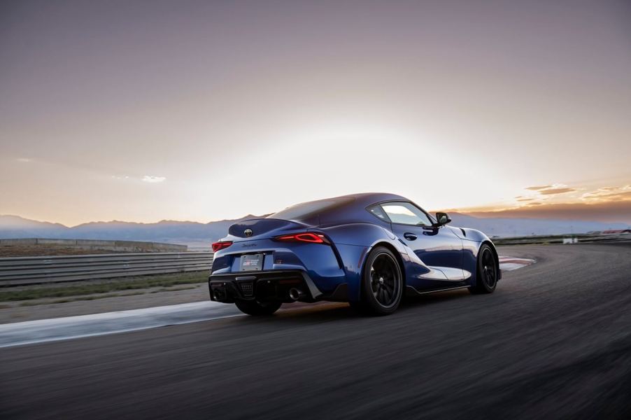 A Mk5 Toyota GR Supra 3.0 takes a sweeping corner on a race track.