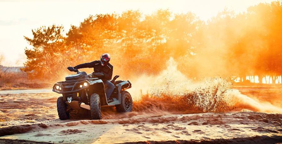 An ATV rider kicks up dirt as they slide their all-terrain vehicle. But they likely can't drive an ATV on the road.