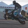 Motorcycle stunt rider Benjamin Baldini leans a bike over in a trick.