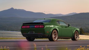 Challenger in F8 Dark green parked in front of a mountain range.