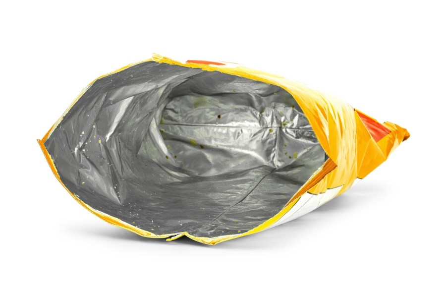 Bright yellow potato chip bag, empty and sitting on a white background.