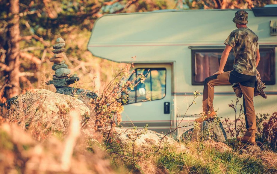 Hunter standing in his campsite, facing an RV camper van.