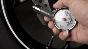 Man uses a tire pressure gauge to check his psi in hot summer weather.