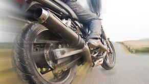 Closeup of a motorcycle riders foot and back tire, the background blurring by