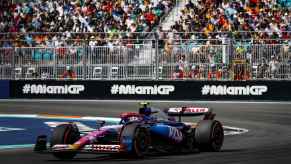 A racecar drives the 2024 F1 Miami Grand Prix with spectator seats in the background