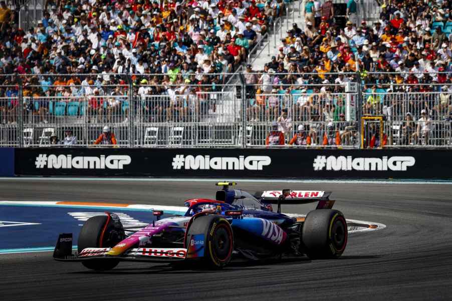 A racecar drives the 2024 F1 Miami Grand Prix with spectator seats in the background