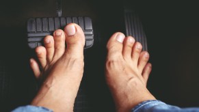 Two bare feet touching car pedals