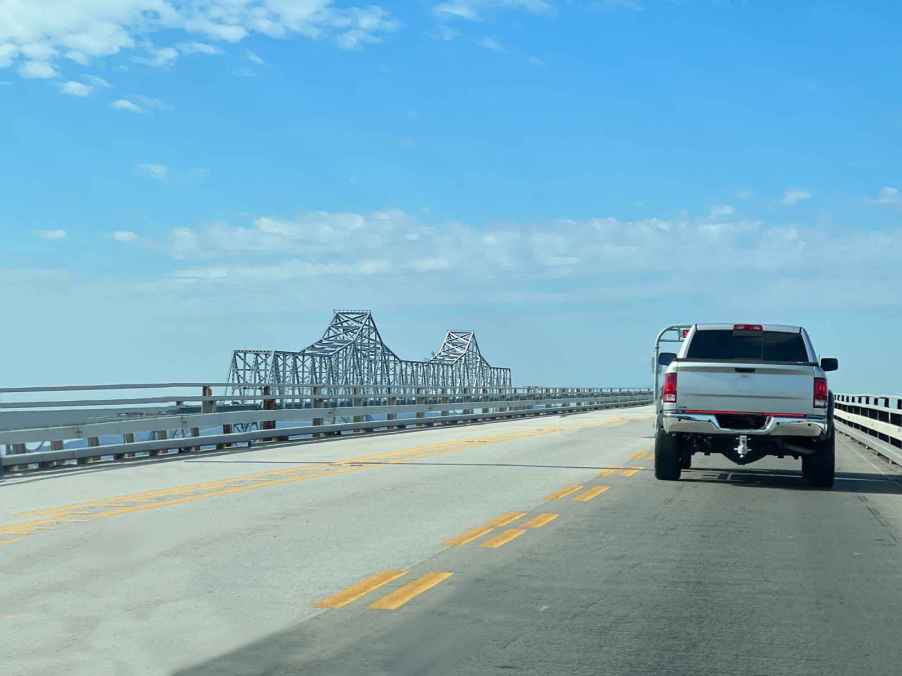 A silver pickup truck driving across the Chesapeake Bay Bridge, known as one of the scariest bridges in the country