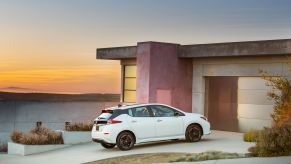 A Nissan LEAF, the cheapest new EV, sits in a driveway.