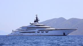 A mega yacht floats off the coast under a cloudless sky.