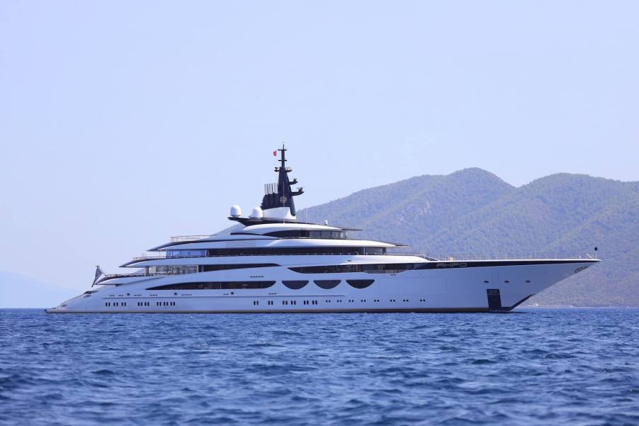 A mega yacht floats off the coast under a cloudless sky.