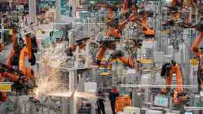 The production line in a BMW factory full of orange robotic arms.