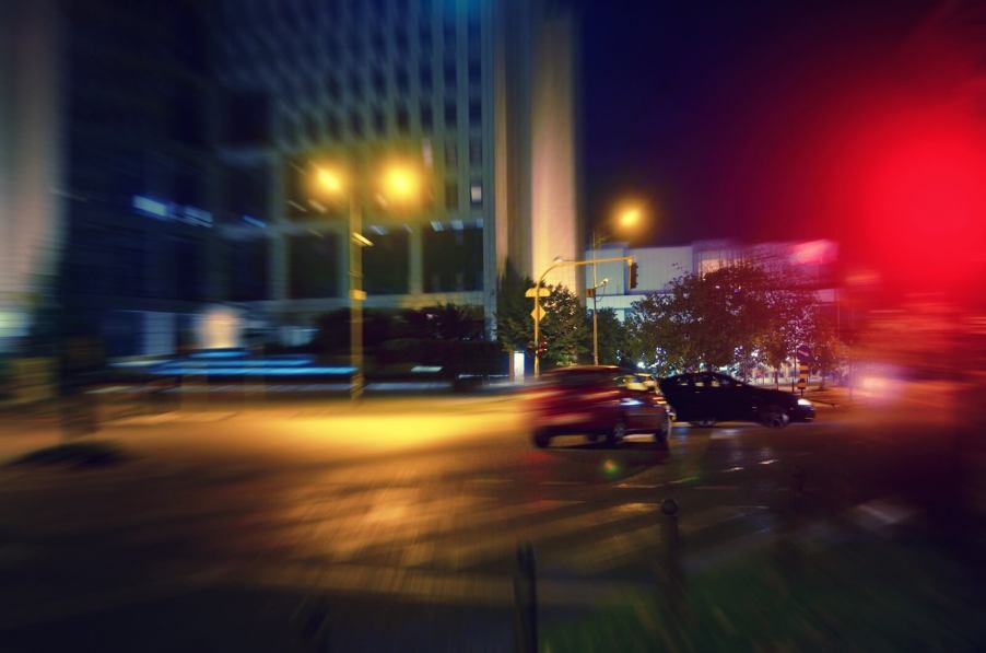 A car running a red light at an intersection at night.