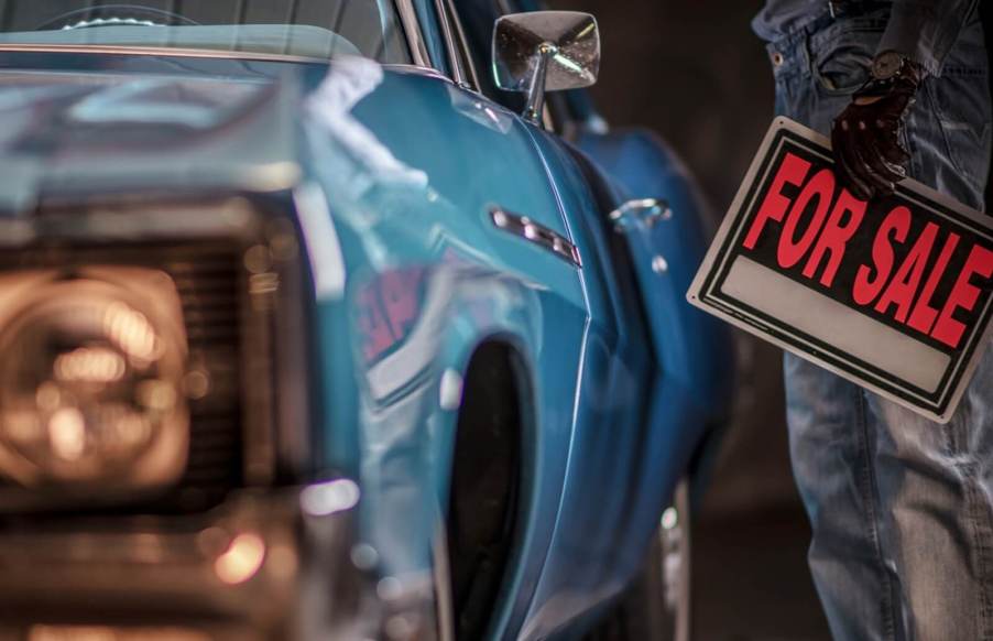 A driver selling a classic car with a for sale sign.