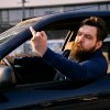 Bearded man giving the middle finger out an open car window.