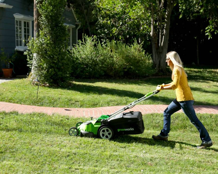 A woman using an electric lawn mower