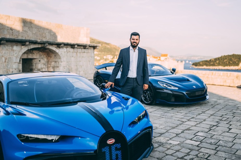 Mate Rimac stands between two cars, parked outdoors.