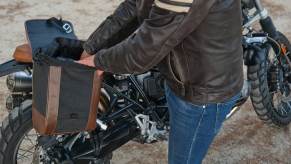 Motorcycle rider reaches into his bike's saddlebag.