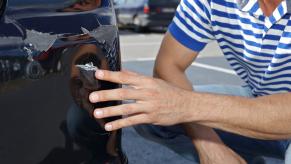 Man points at a dented rear bumper from a crash while parallel parking.