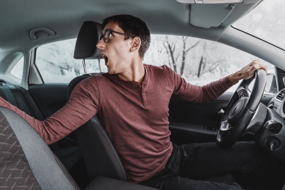 Driver looks over his shoulder in shock as he crashes while parallel parking