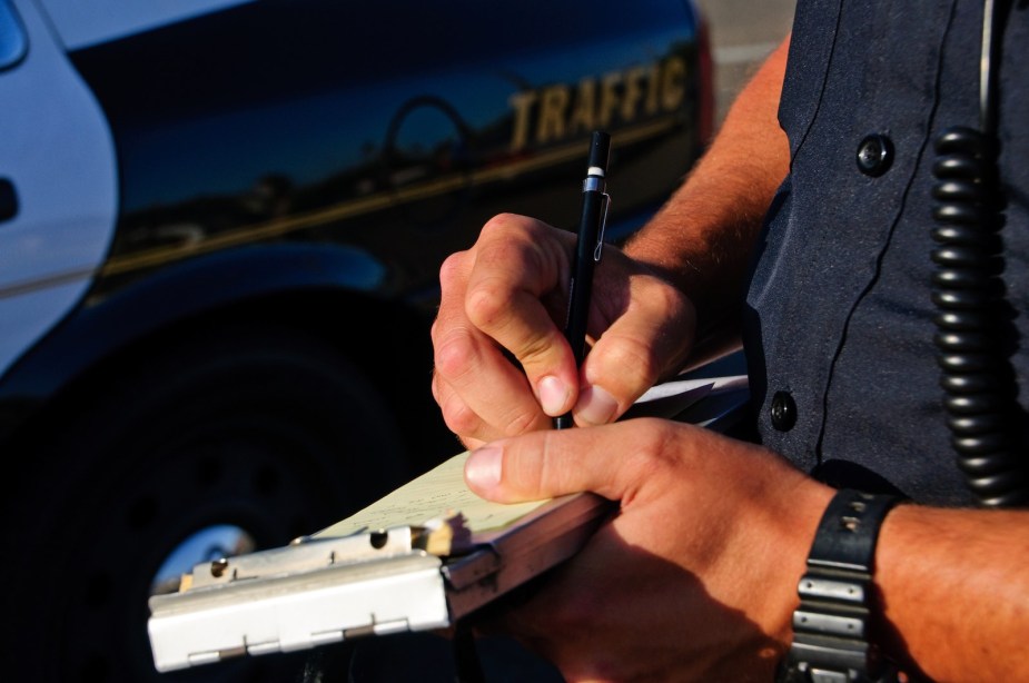 The hands of a police officer writing a ticket for a traffic stop