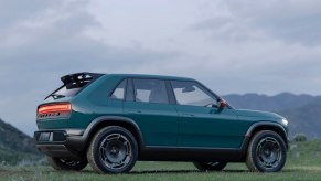 Blue Rivian crossover EV concept car parked in a field, a cloudy sky visible in the background.