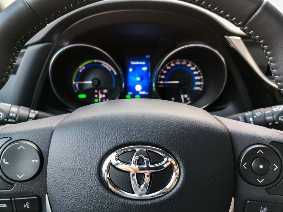 The Toyota logo on the steering wheel of a compact car.