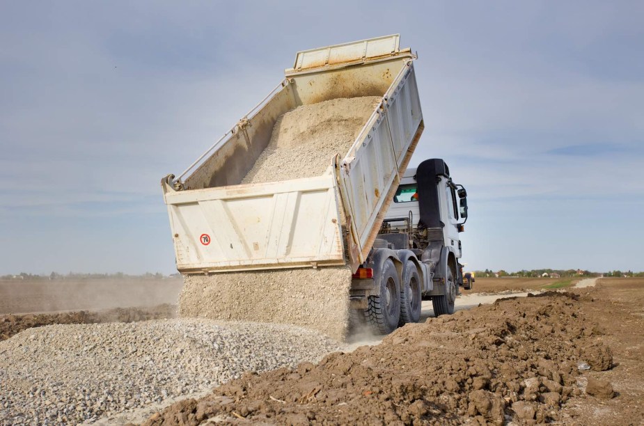 Dump truck hauls gravel into a road construction site.