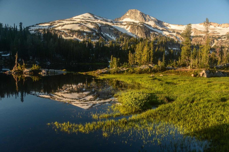 Snow-capped mountain range in rural Oregon, a lake in the foreground.