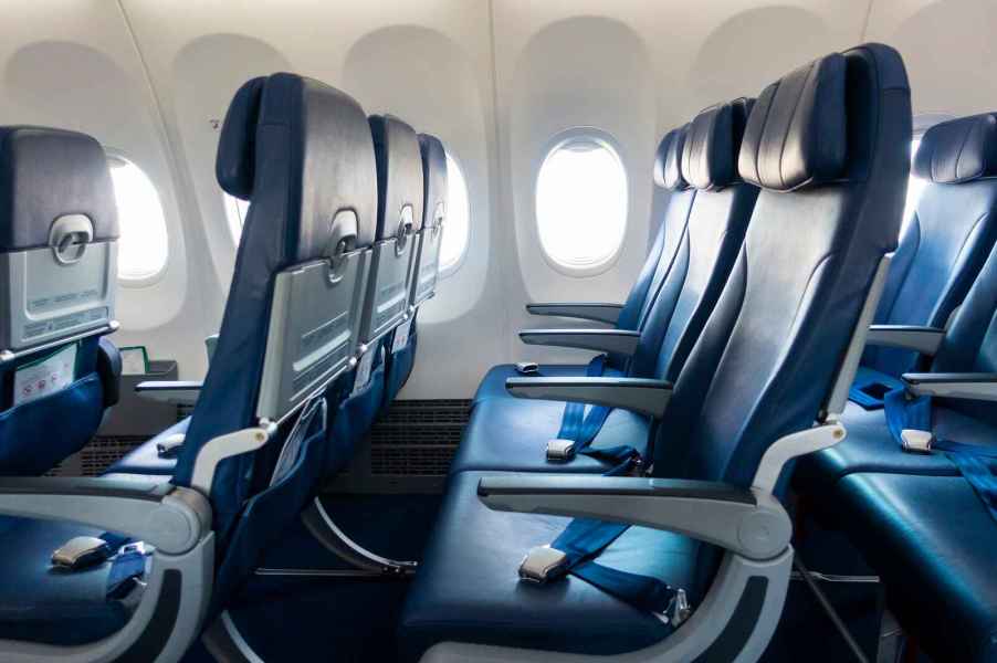 Rows of blue airplane seats shown in profile view facing left frame most airlines make "larger" passengers book a flight by paying for two seats