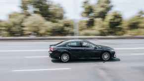 A black Toyota Camry sedan driving fast on a highway