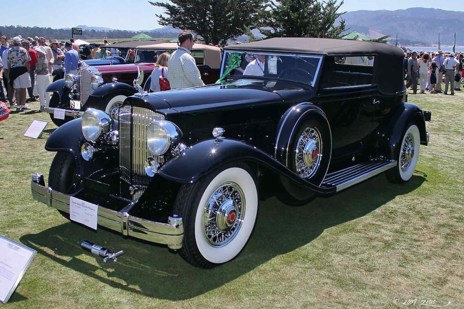 Black 1932 Packard convertible car parked on a grass field during a car show.