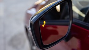 The blindspot detection monitor on the mirror of a Nissan sedan.