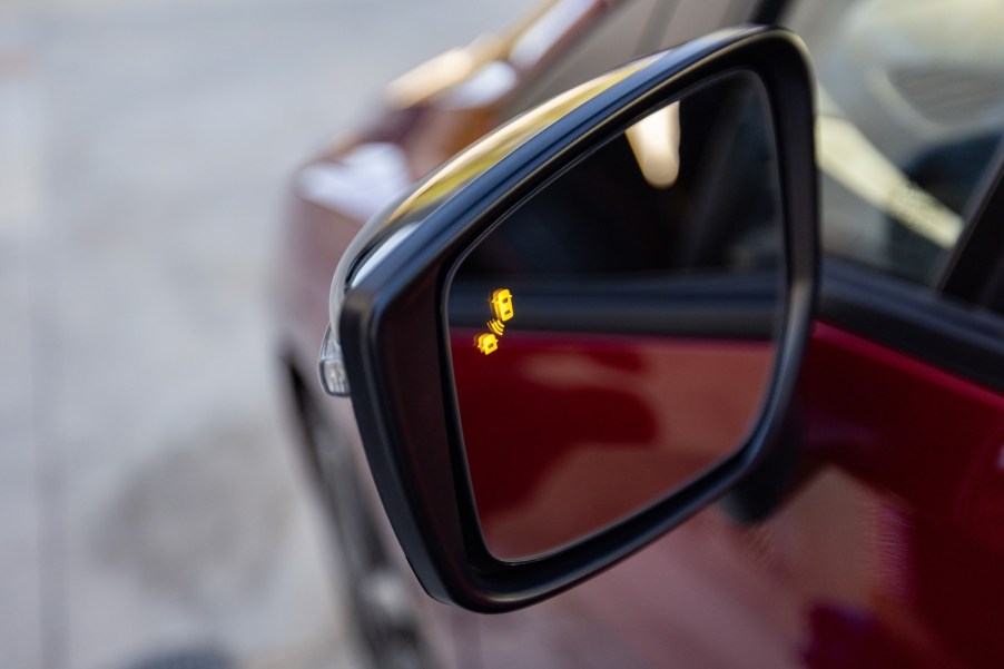 The blindspot detection monitor on the mirror of a Nissan sedan.