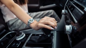 A driver puts her hand on the lever of an automatic transmission