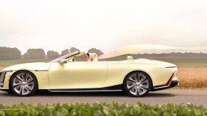 Woman drives a yellow Cadillac convertible concept EV down a country road.