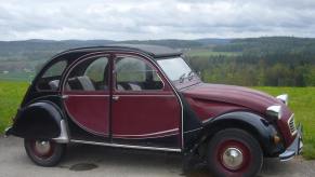 Red and black Citroen 2CV parked on a mountaintop.