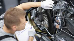 A person inspect a motorcycle for safety and function with the T-CLOCS acronym.