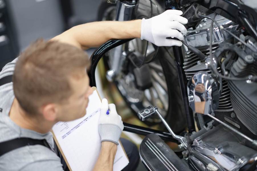 A person inspect a motorcycle for safety and function with the T-CLOCS acronym.