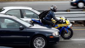 A motorcycle riding between fast-moving highway traffic as he splits lanes in California