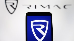 The Rimac logo on a cellphone in front of a Rimac sign.