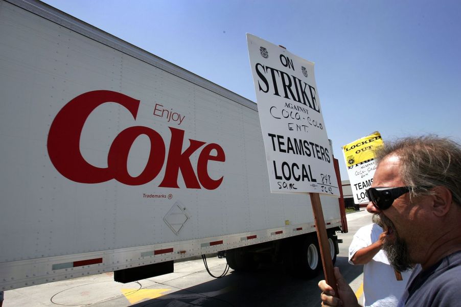 Teamster truck drivers strike outside a coca cola bottling plant, a semi truck driving past